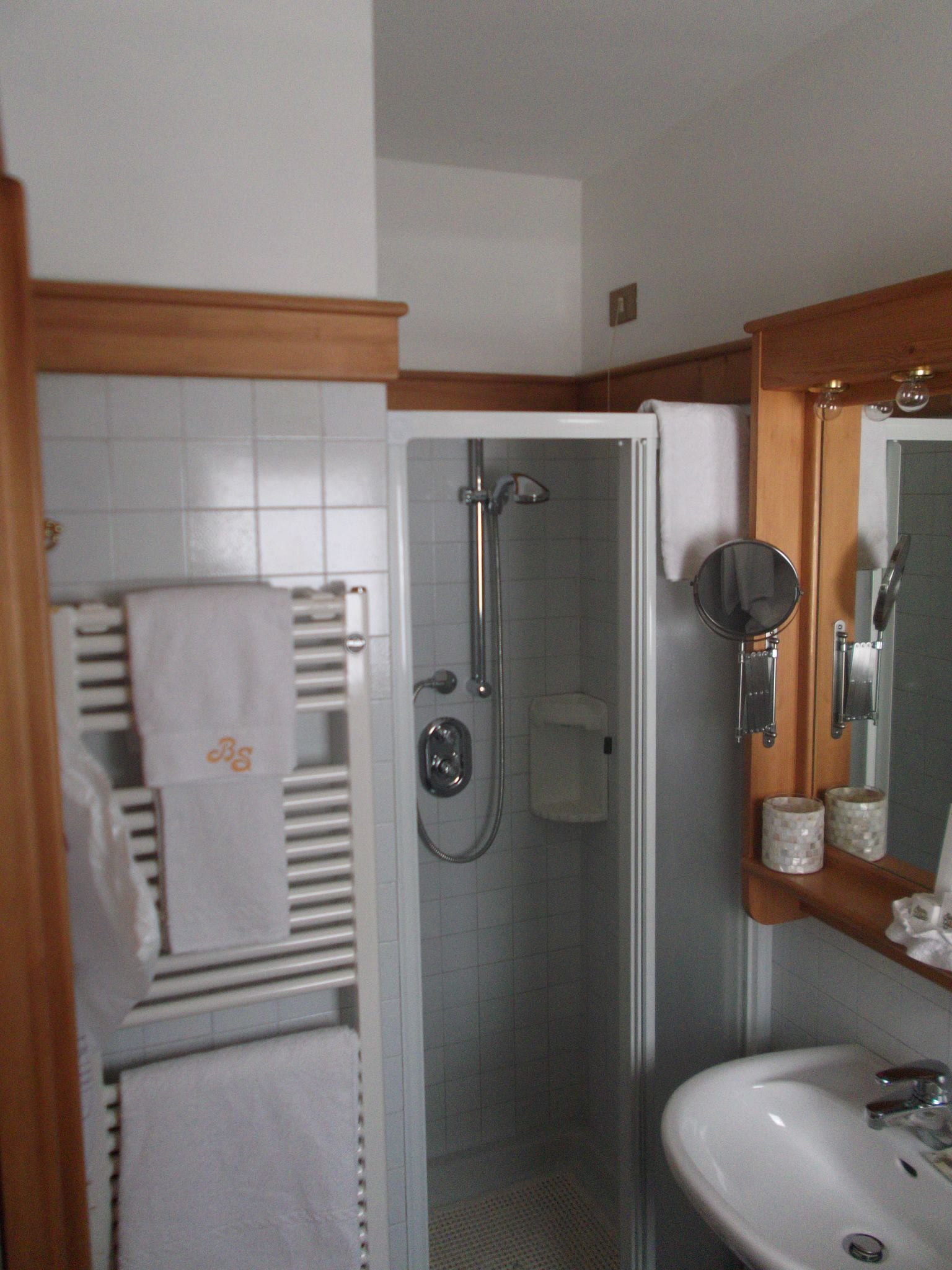 Un baño con ducha envuelta en vidrio, un lavabo blanco y un espejo encima.