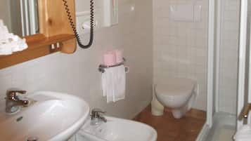 Un baño con techo de madera, lavamanos, bidé, inodoro y zona de ducha.