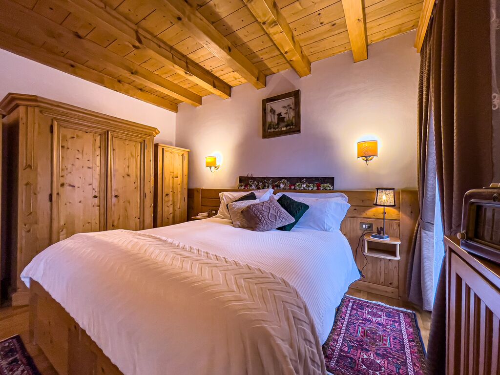 Un dormitorio con una cama grande, cabecera de madera, dos mesitas de noche y un velador.