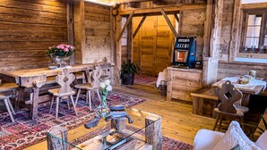 A rustic wooden interior with a dining area, a coffee machine, and a patterned rug. - Hotel da Beppe Sello (Cortina d'Ampezzo)