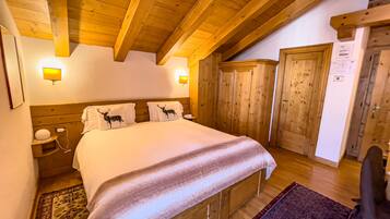 Une chambre à coucher en bois, avec un grand lit, deux tables de chevet, une commode, une armoire et une porte avec une pancarte.