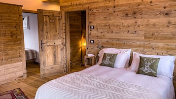 Una habitación con paneles de madera, una cama, una puerta y una mesita de noche.