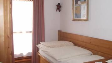 Un dormitorio con una cama de madera, una mesita de noche pequeña, un cuadro enmarcado en la pared y una alfombra estampada en el suelo.