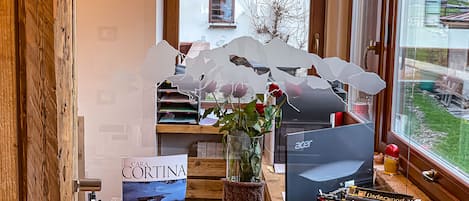 Un escritorio con una computadora, una máquina de escribir, un florero con rosas y un libro titulado "Cara Cortina".