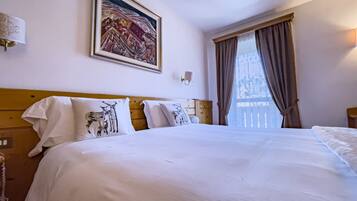 A hotel room with a large bed, a painting on the wall, and a window with curtains.