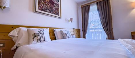 Una habitación de hotel con una cama grande, un cuadro en la pared y una ventana con cortinas.