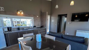 Una cocina moderna con comedor, sofá y televisor.