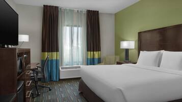 Quarto de hotel com uma cama grande, uma escrivaninha com cadeira, televisão e janela com cortinas.
