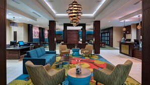 A hotel lobby with a blue sofa, wicker chairs, a blue coffee table, and a colorful carpet. - Fairfield Inn & Suites by Marriott Austin Northwest/Research Blvd (Austin)