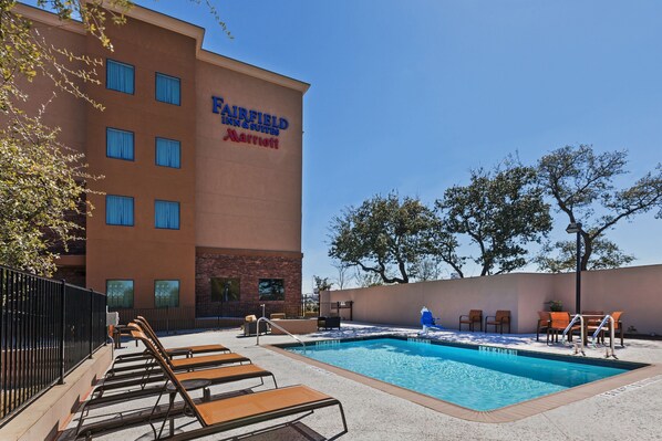A Fairfield Inn & Suites Marriott pool area with lounge chairs, a pool, and a brick building facade. - Fairfield Inn & Suites by Marriott Austin Northwest/Research Blvd (Austin)