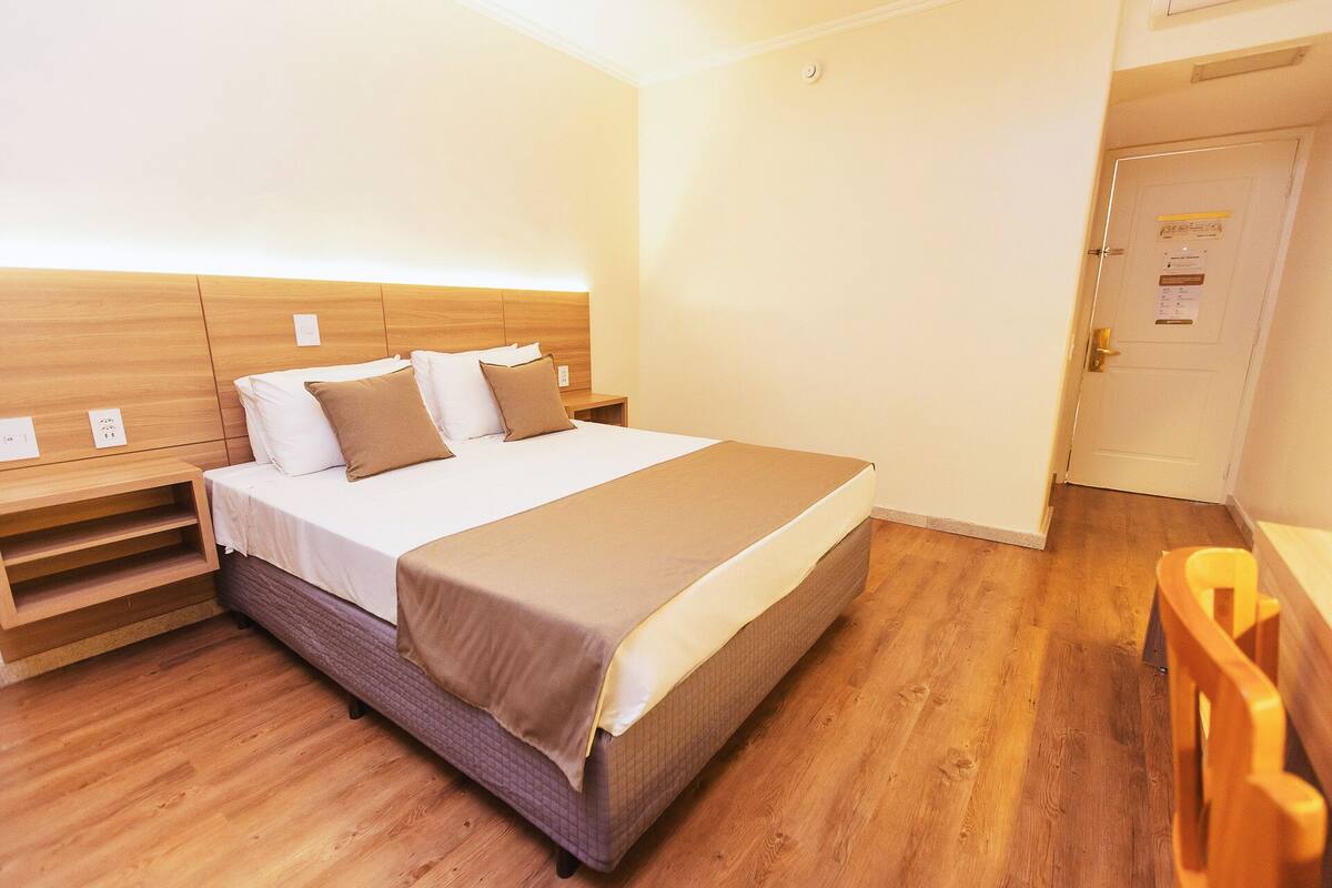 A bedroom with a bed, wooden headboard, bedside tables, and a door with a sign.