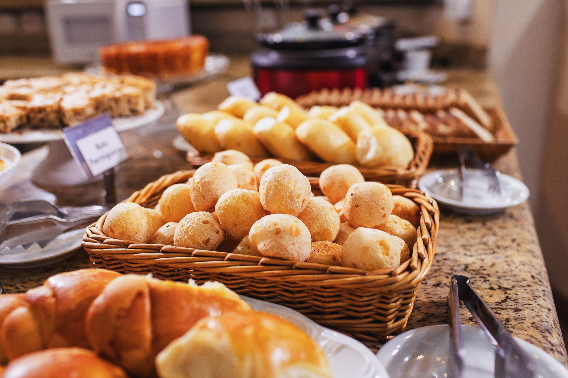 Un bufé con diversos productos horneados, incluyendo panecillos y pastelería.