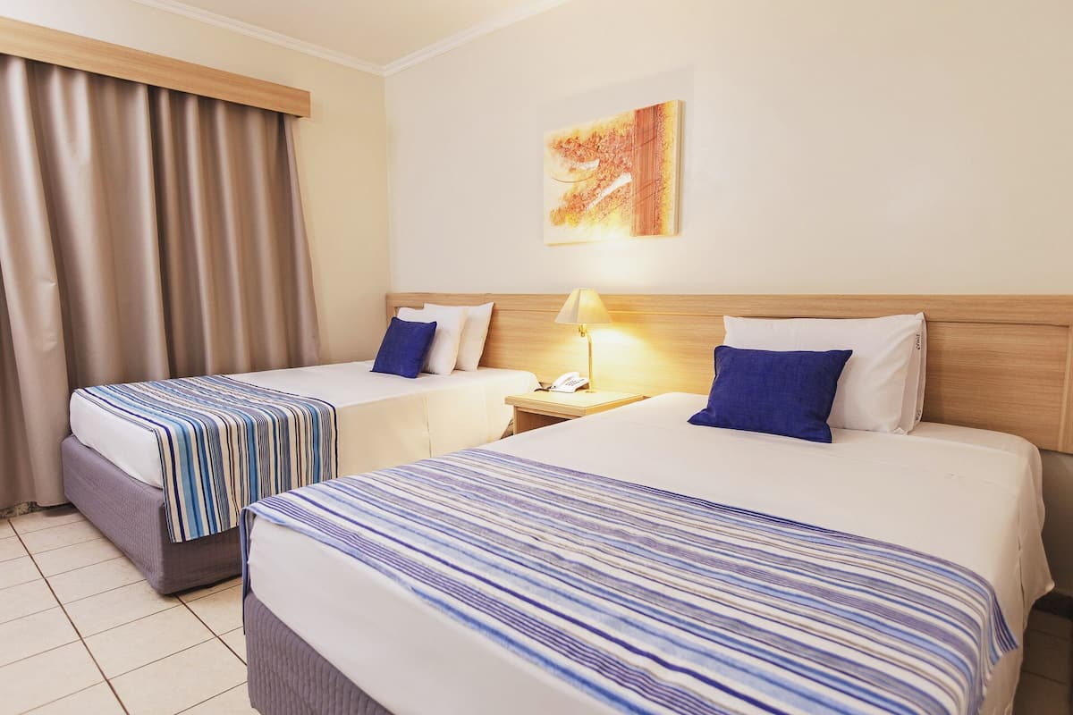 A hotel room with two beds, a nightstand with a lamp, and a painting on the wall.