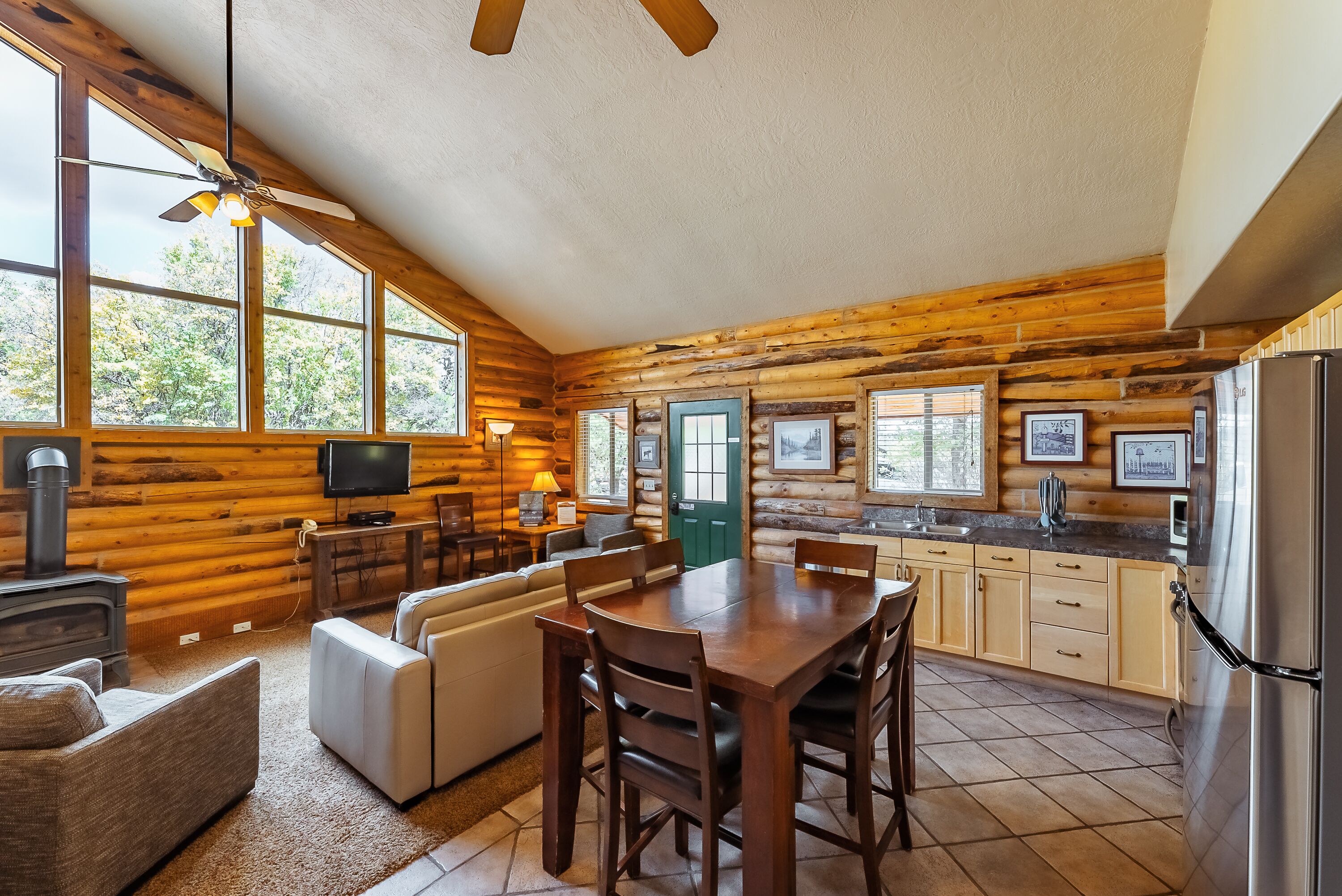 A log cabin interior with a dining area, kitchen, and living room.