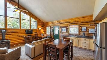 A log cabin interior with a dining area, kitchen, and living room.