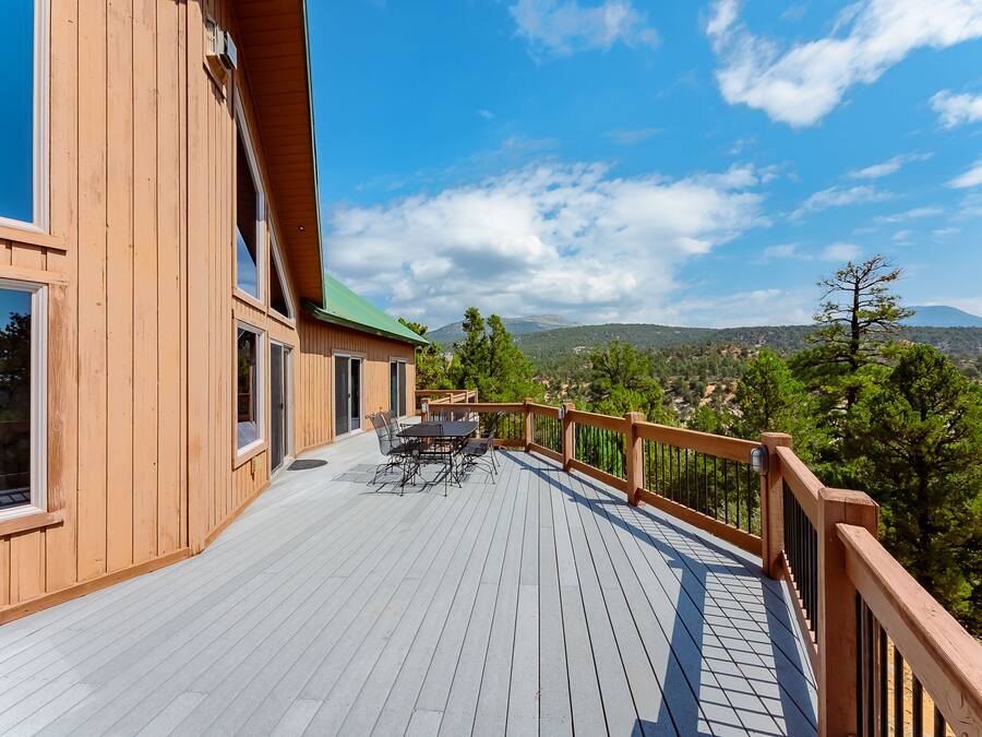 Une terrasse en bois avec un espace repas et une vue sur les montagnes.