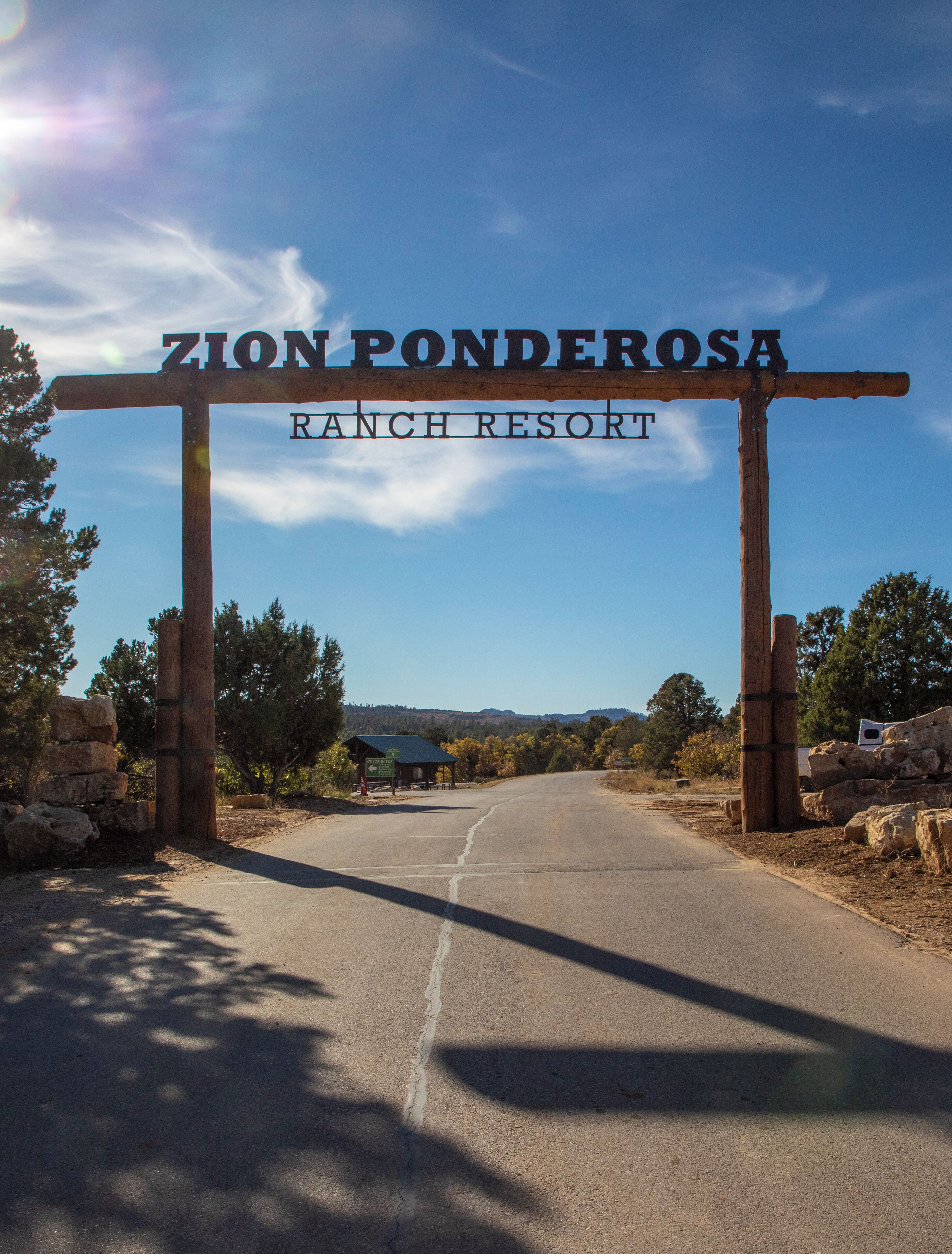 A wooden sign with 'ZION PONDEROSA RANCH RESORT' written on it, indicating the entrance to a ranch-style property.