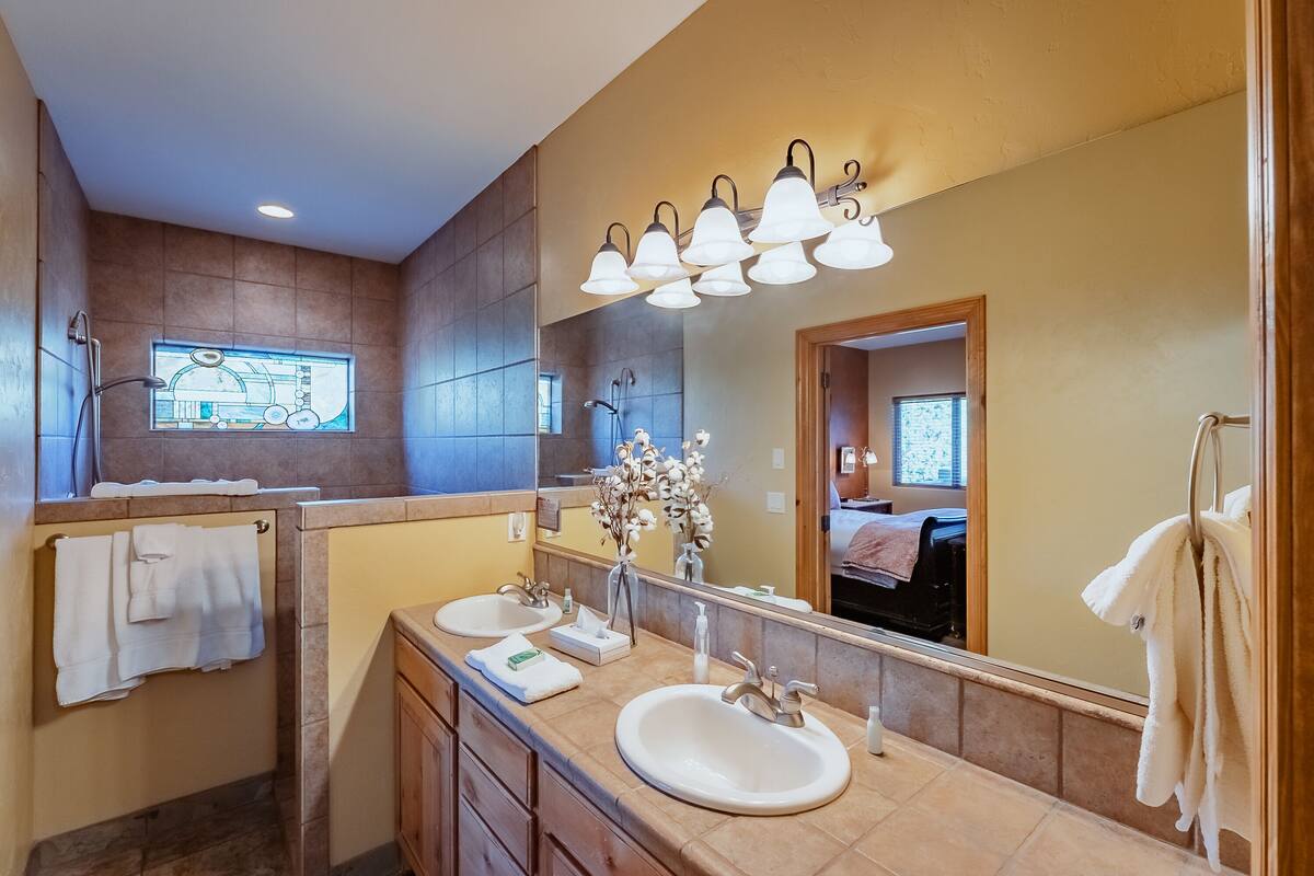 A bathroom with two sinks, a large mirror, and a window with a stained glass design.
