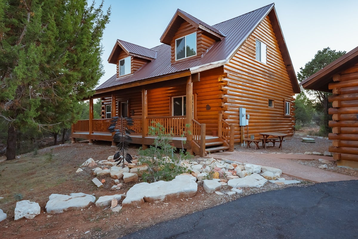 A log cabin with a porch, a small deck, and a stone pathway leading to the entrance.