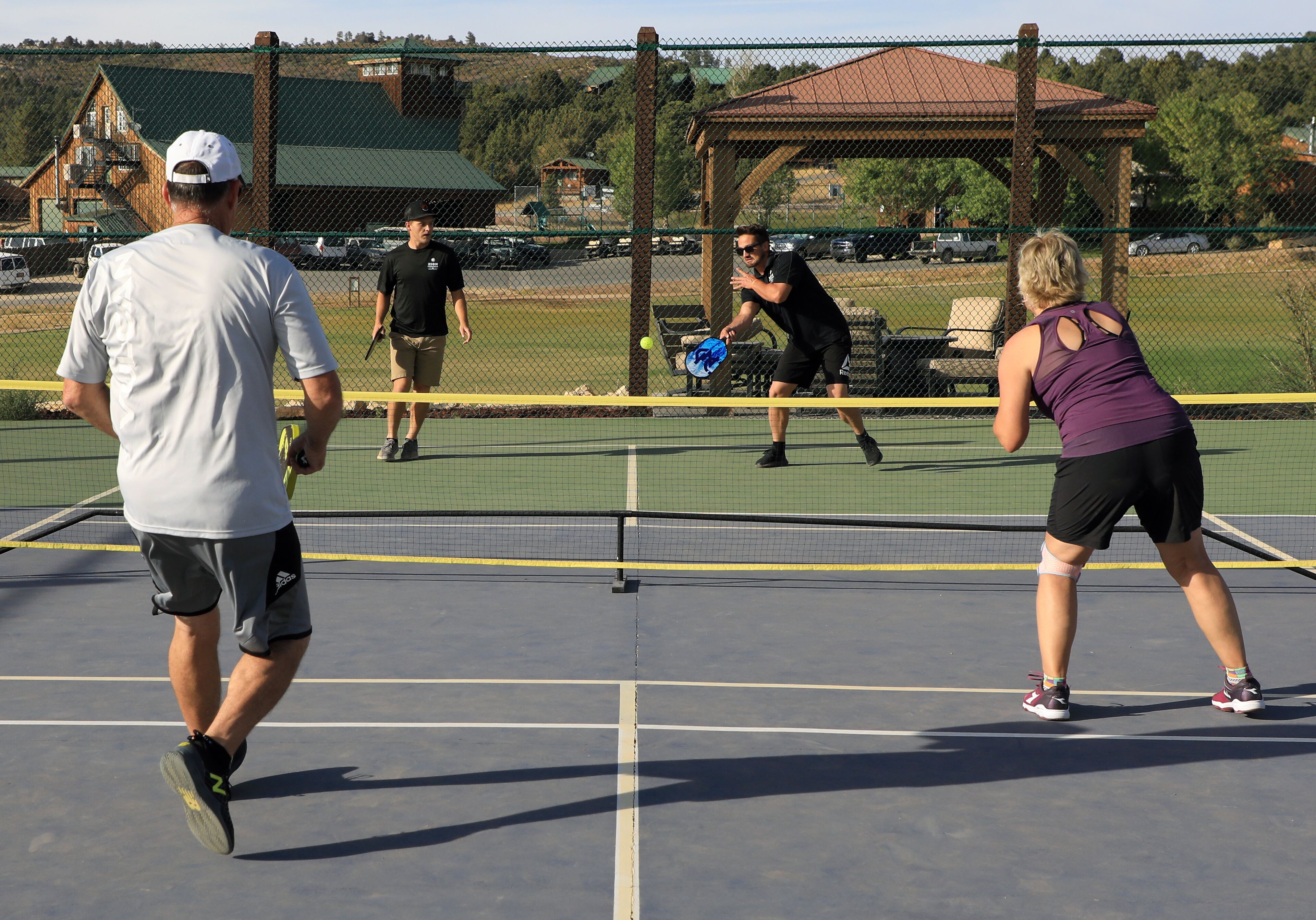 Un terrain de tennis avec un filet, un kiosque et une clôture.