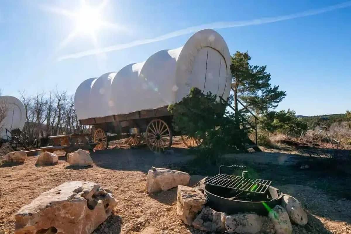 A large white cylindrical structure with a trailer attached, set in a dry, rocky landscape with sparse vegetation.