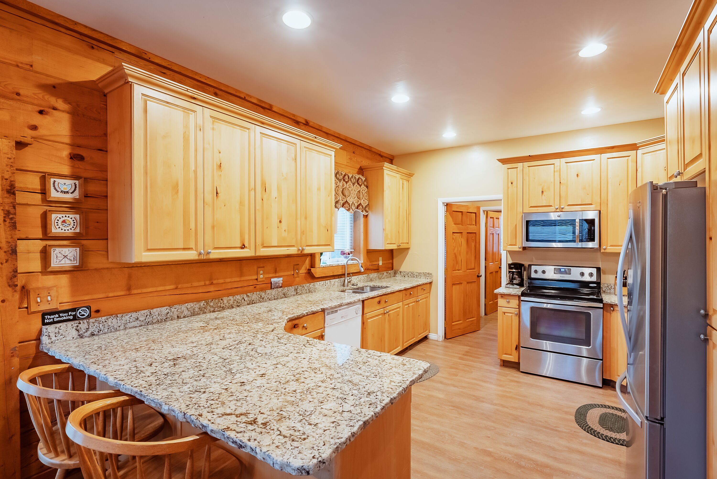 A kitchen with wooden cabinets, granite countertops, a microwave, an oven, and a refrigerator.