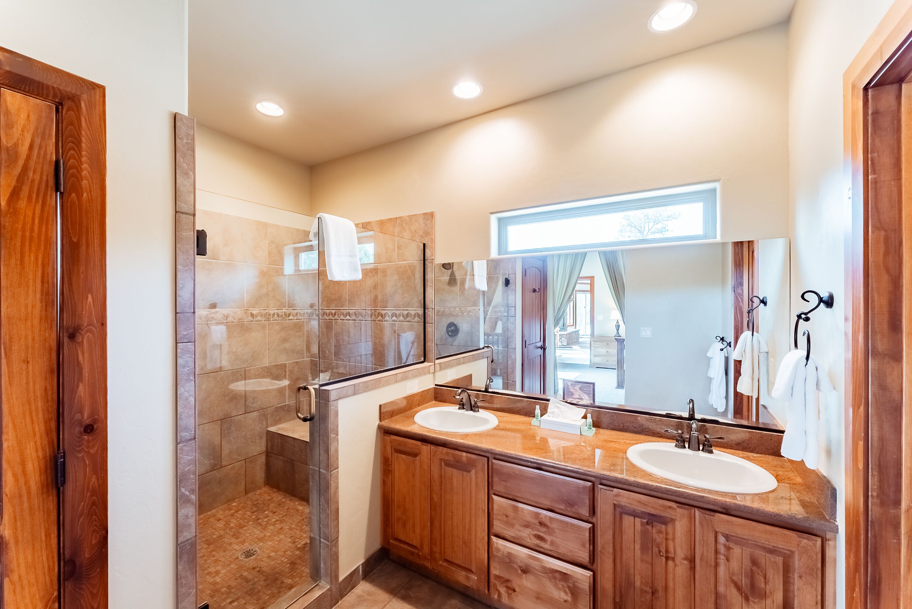 Une salle de bain moderne avec deux lavabos, un grand miroir et une douche à parois de verre.