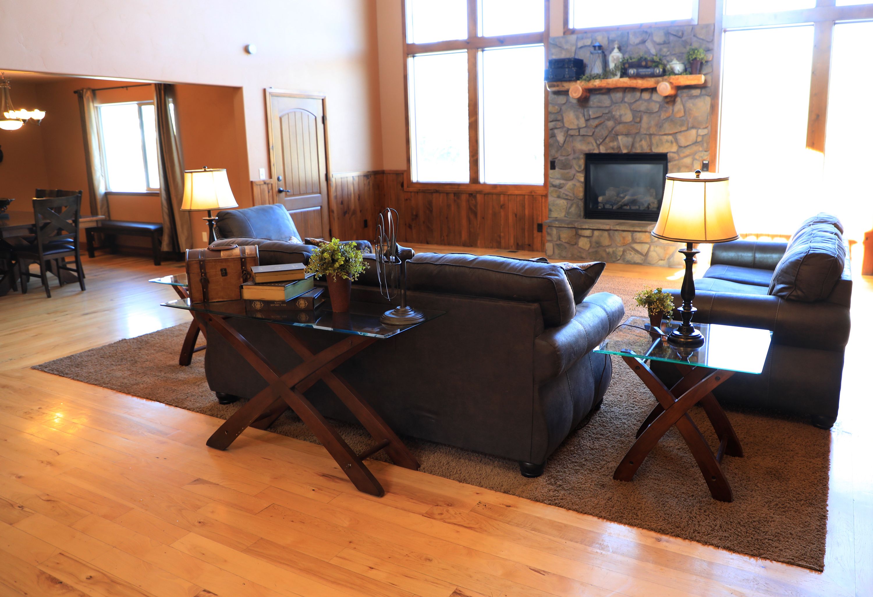 A spacious living room with a fireplace, wooden flooring, and a large window providing natural light.