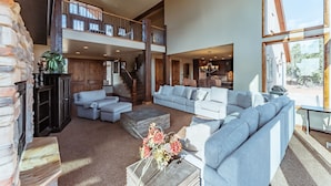 Een ruime woonkamer met een open haard, een grote zithoek en uitzicht op het omliggende landschap.
