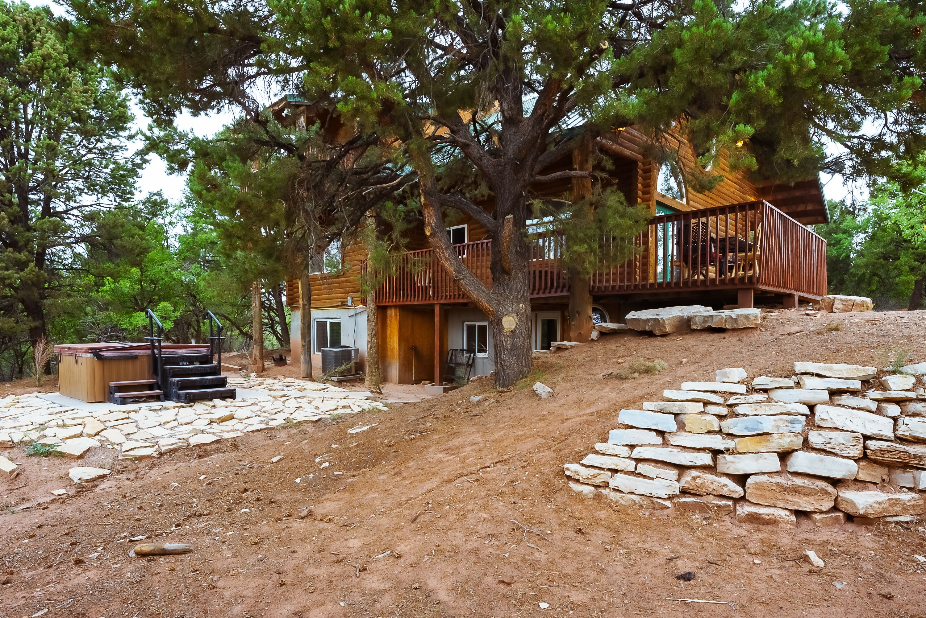 A log cabin with a stone pathway leading to the entrance, surrounded by trees.
