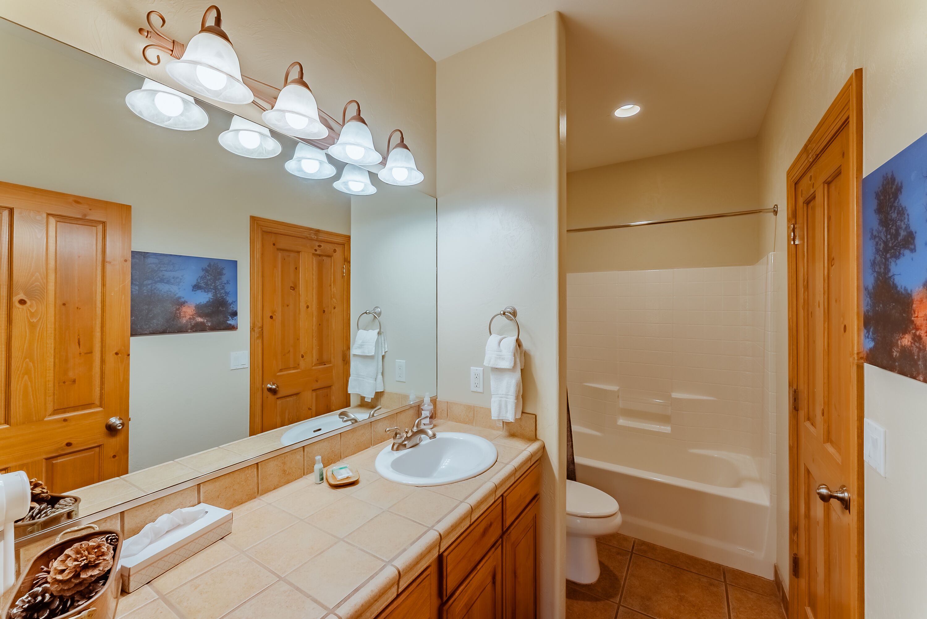 A bathroom with a large mirror, a sink, a toilet, and a bathtub.