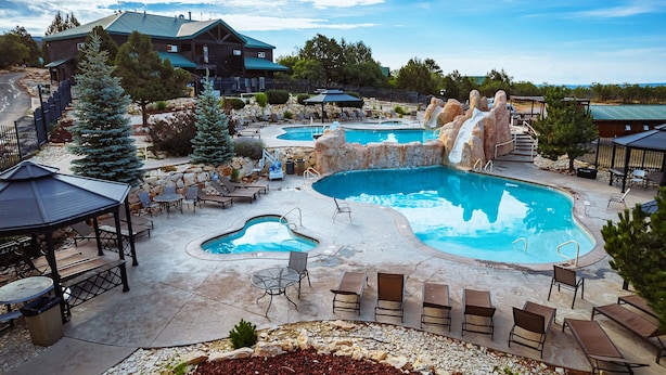 Een resort met diverse zwembaden, comfortabele zitgedeeltes en een grote rotsformatie.