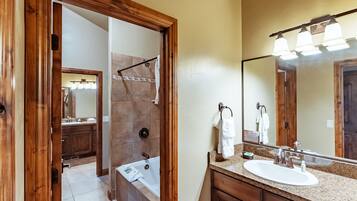 A bathroom with a wooden door, a sink, a mirror, and a shower area.