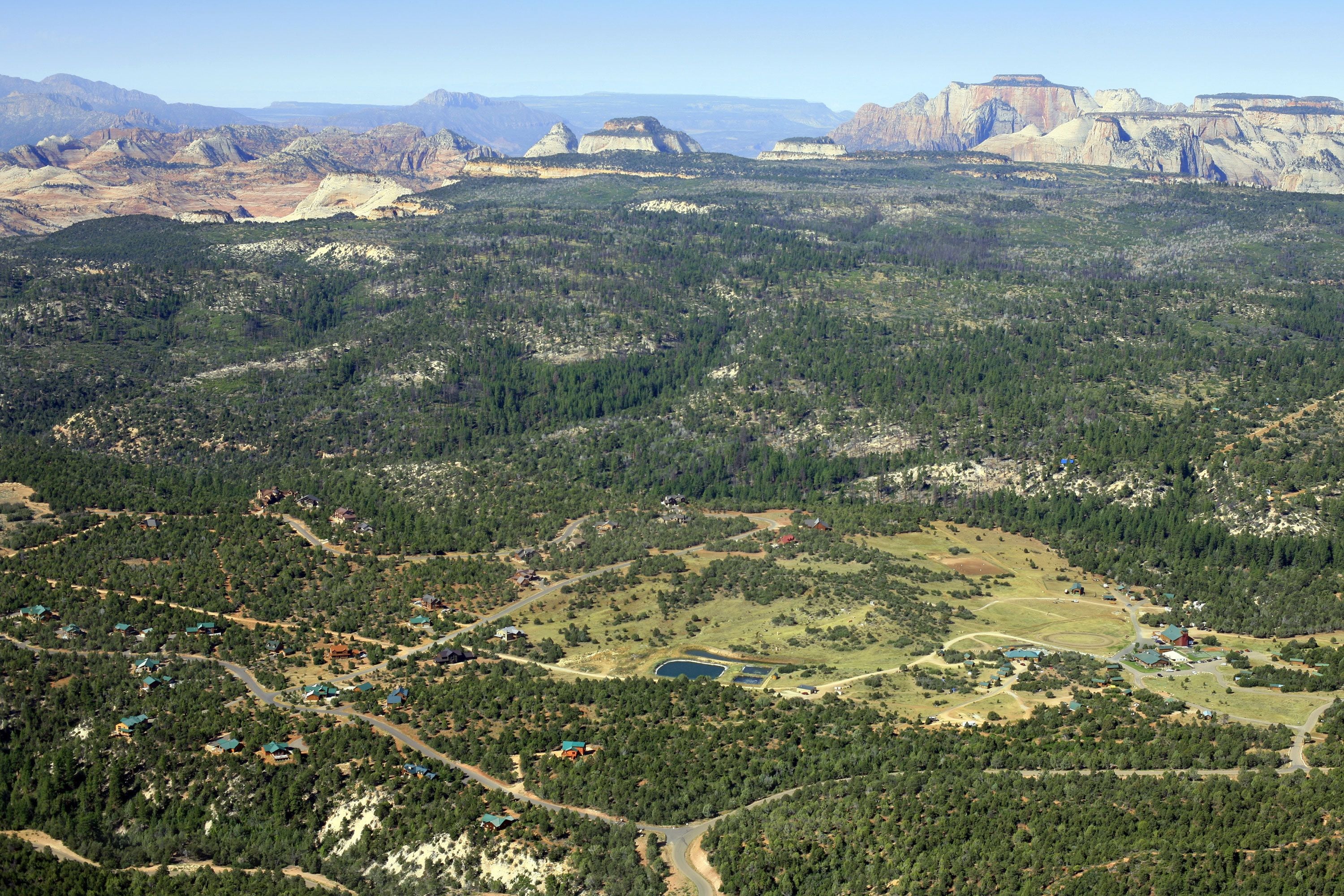 An aerial view of a mountainous area with scattered houses and a small lake.