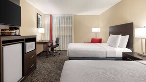 A hotel room with a bed, a desk with a computer, a TV, and a minibar. - Ramada by Wyndham Alpena (Alpena)