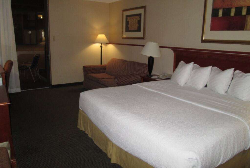 Habitació d'hotel amb un llit gran, un escriptori, una cadira i una làmpada.