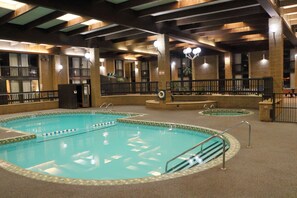 An indoor swimming pool with multiple lanes, a lifeguard station, and a seating area with a view of the pool. - Ramada by Wyndham Alpena (Alpena)