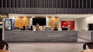 A breakfast area with a counter, seating, and a refrigerator. - Ramada by Wyndham Alpena (Alpena)