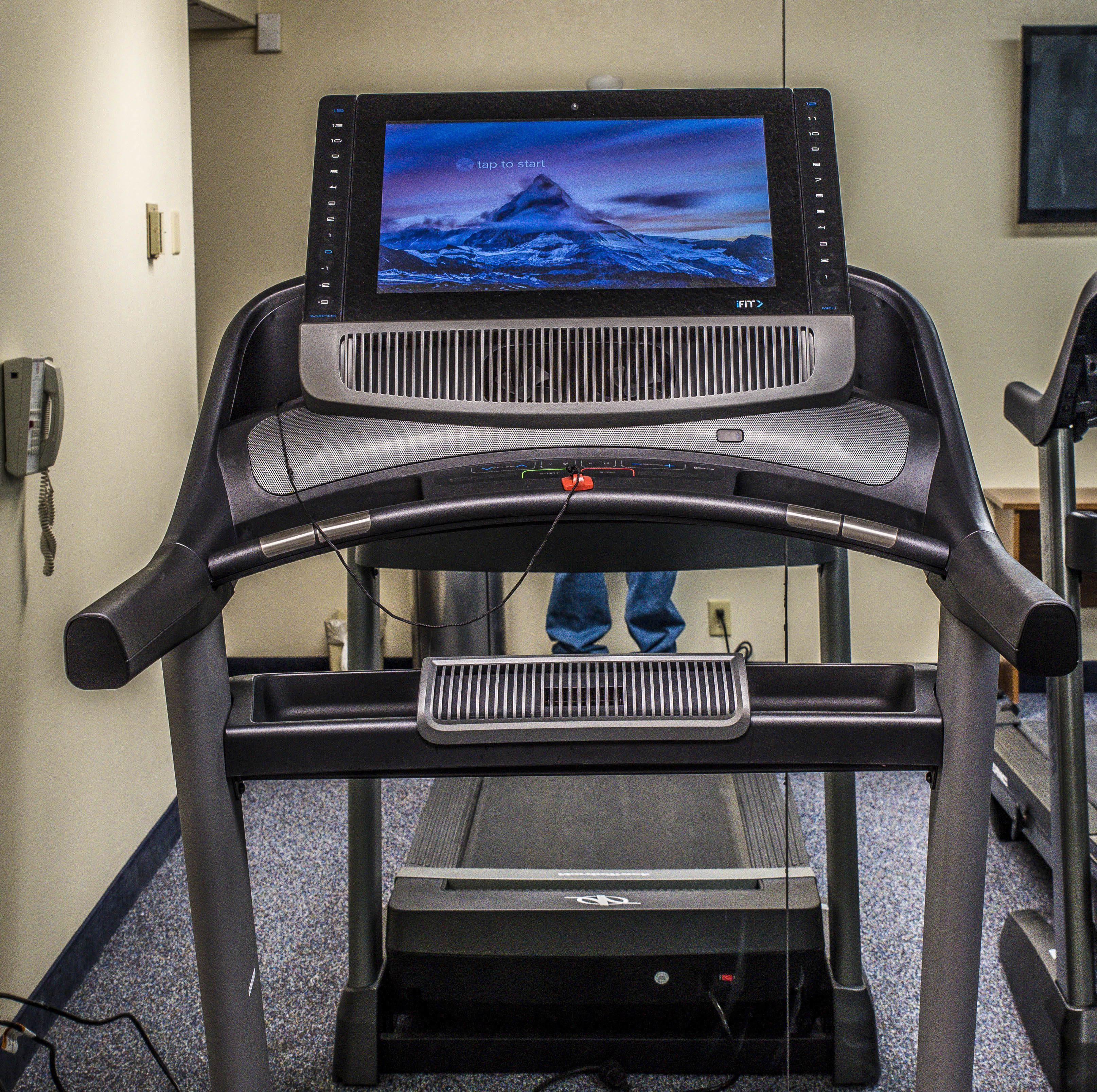 A treadmill with a digital screen displaying a landscape image.