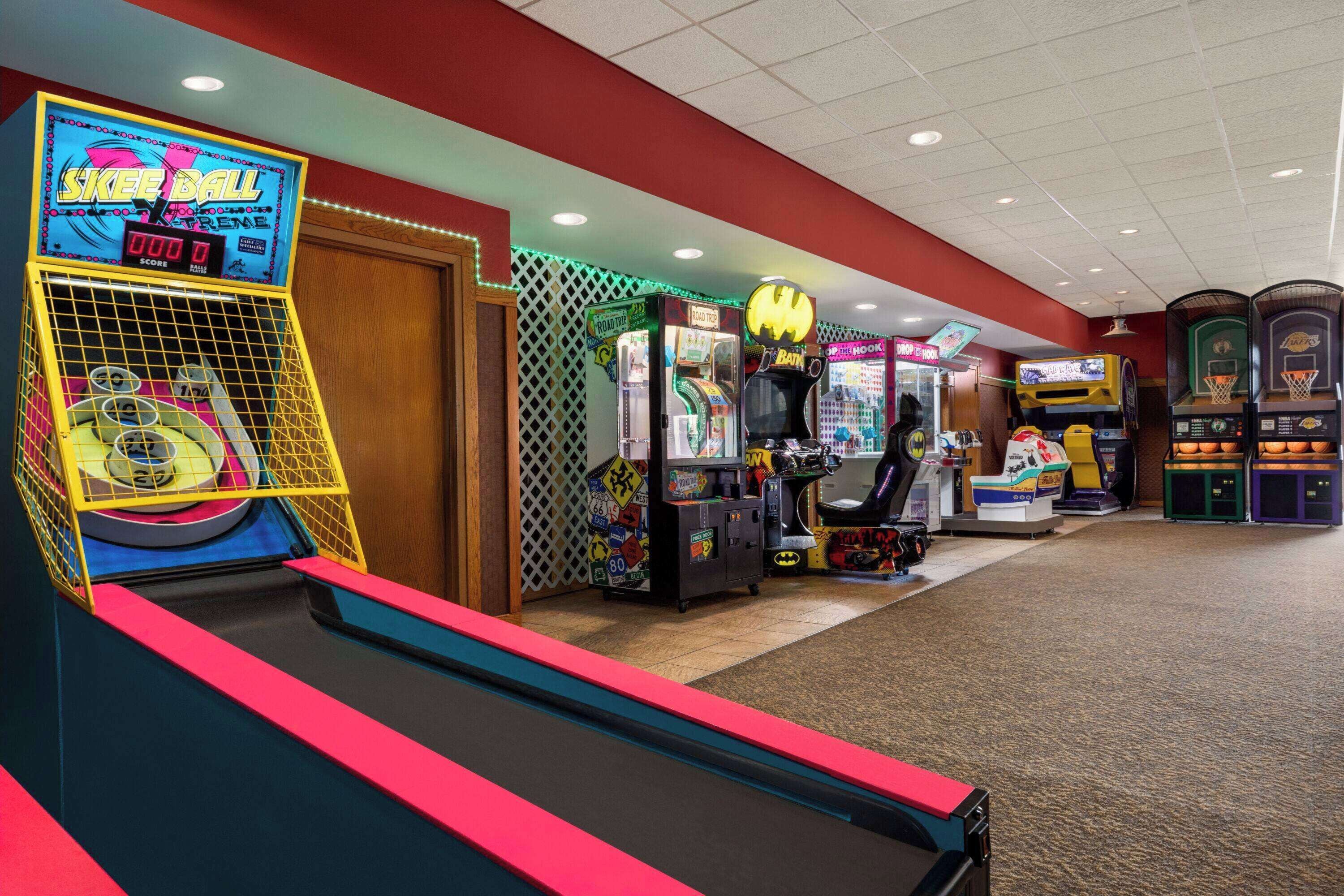 An indoor arcade with various gaming machines, including a skateboarding game and a Batman-themed game.