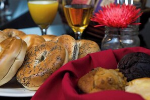 A variety of bagels and pastries on a plate, with a glass of orange juice and a glass of wine in the background. - Hotel Marshfield, BW Premier Collection (Marshfield)
