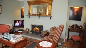 Una sala de estar acogedora con chimenea, televisor, estantería y un sillón cómodo.