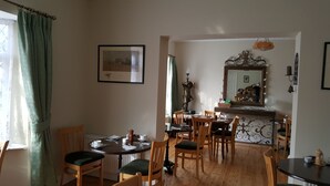 Un comedor con mobiliario de madera, una mesa con sillas, un cuadro enmarcado en la pared y un espejo sobre la mesa.
