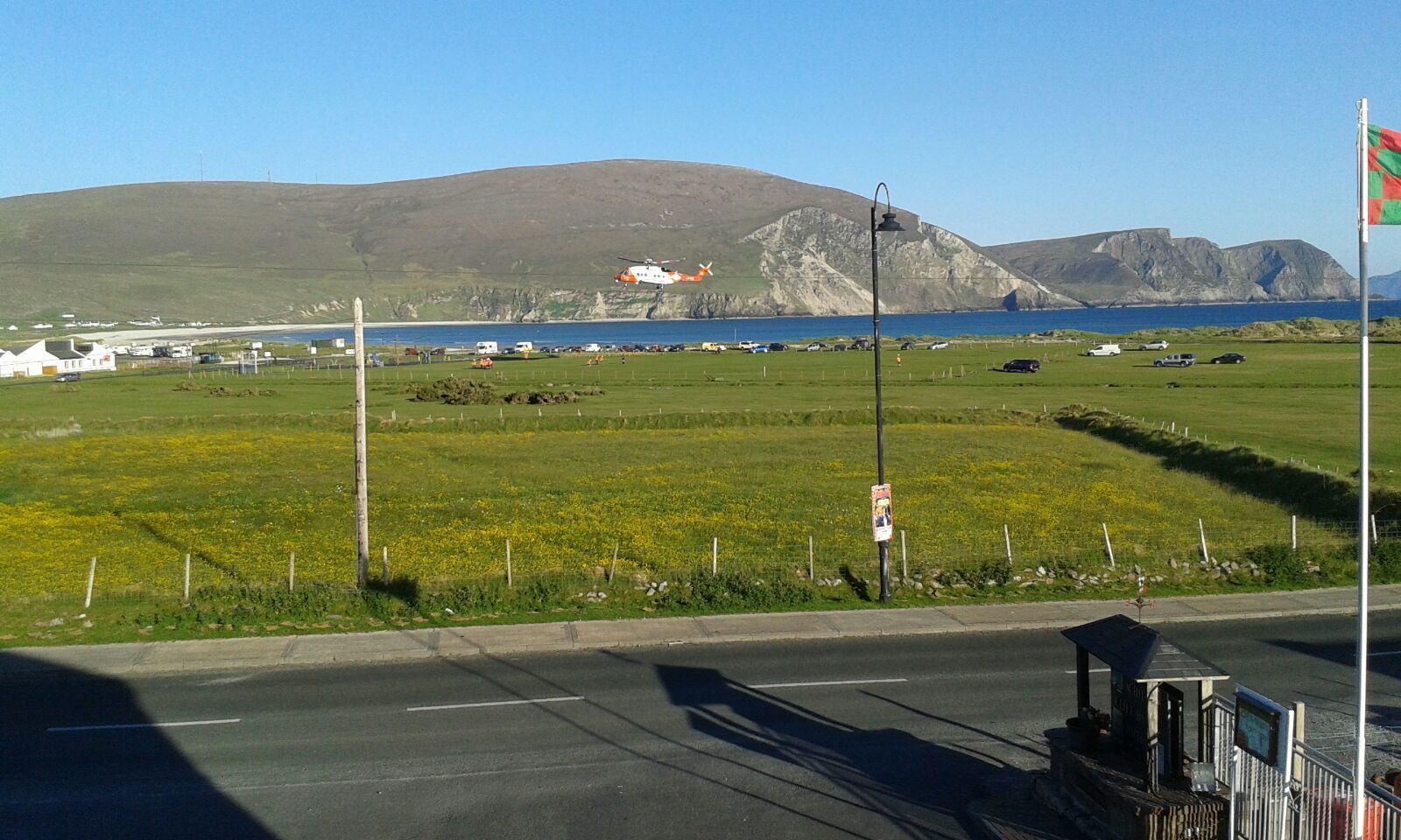 A rural landscape with a road, a small building, and a flag.