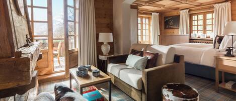 A cozy room with a bed, a sofa, a chair, and a wooden table.