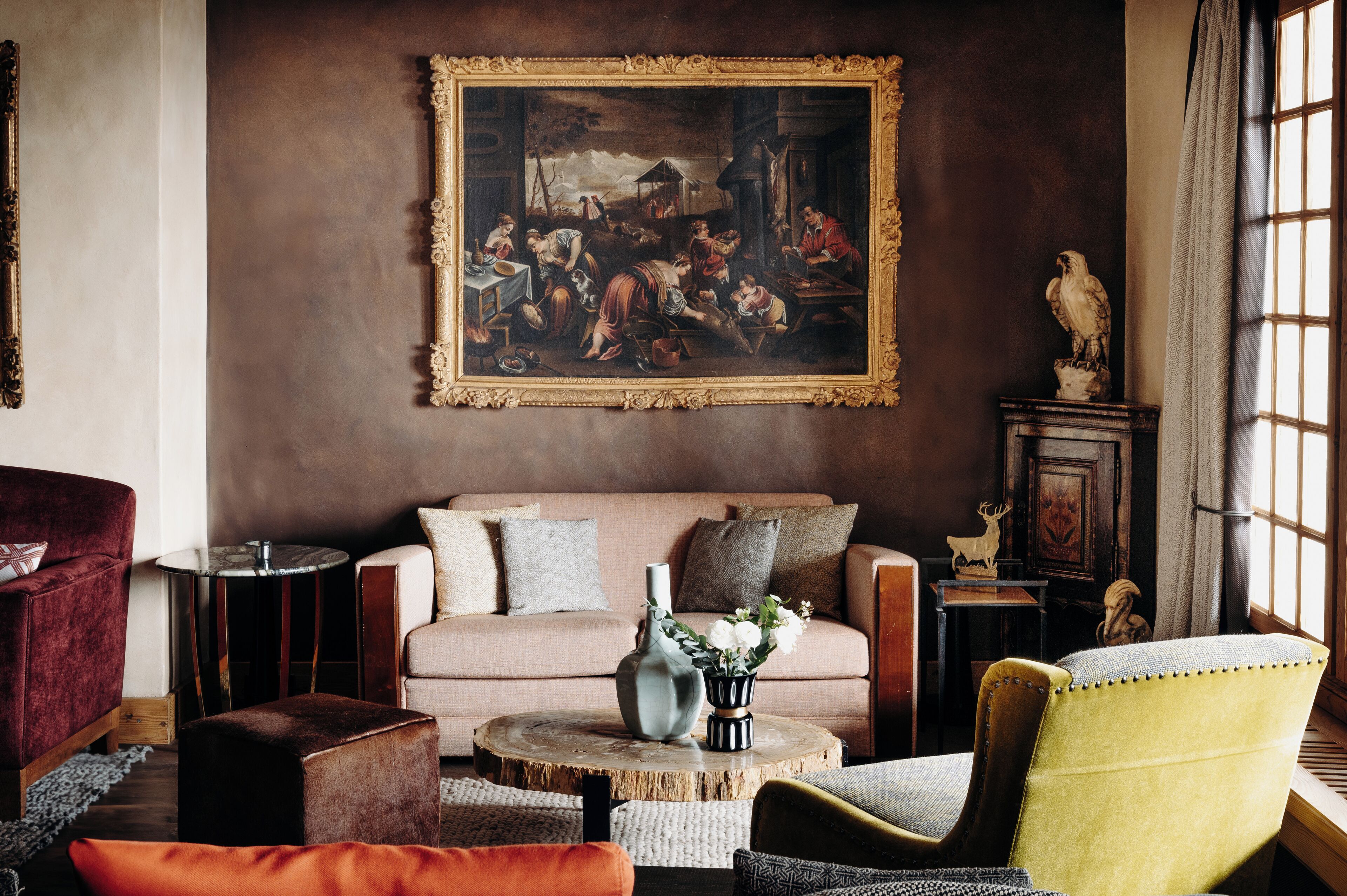 A living room with a large classical painting, a sofa, and various decorative items.