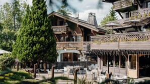 Un edificio in legno con balconi, sedute all'aperto e un giardino.
