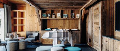 A cozy wooden interior with a seating area, bookshelves, and a unique white animal-shaped table.