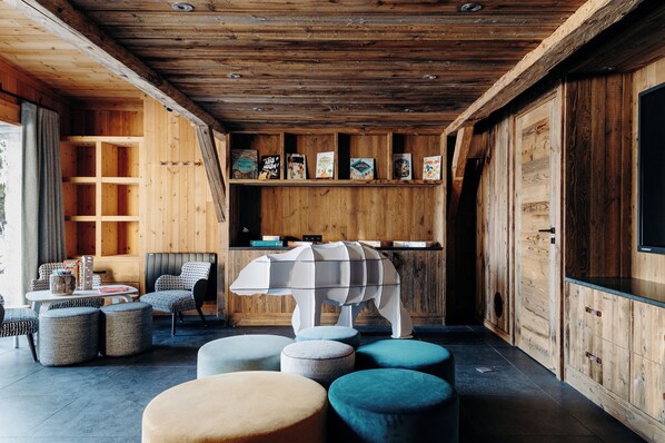 A cozy wooden interior with a seating area, bookshelves, and a unique white animal-shaped table.