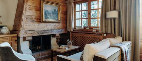 Interior acogedor de una cabaña con chimenea, paredes de madera, un sofá y una mesa con adornos.